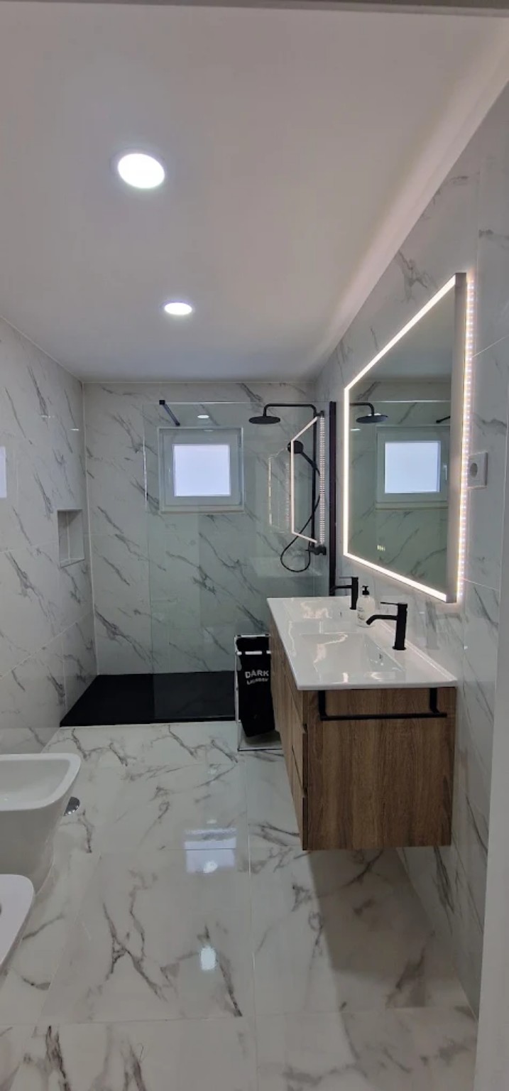 Casa de banho com revestimento efeito mármore e torneiras pretas